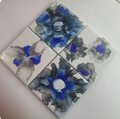 Set of four ceramic tiles with blue and gray floral designs on a white background